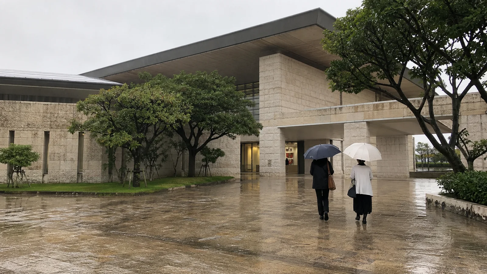 雨に濡れた広場から文化施設へ向かう二人
