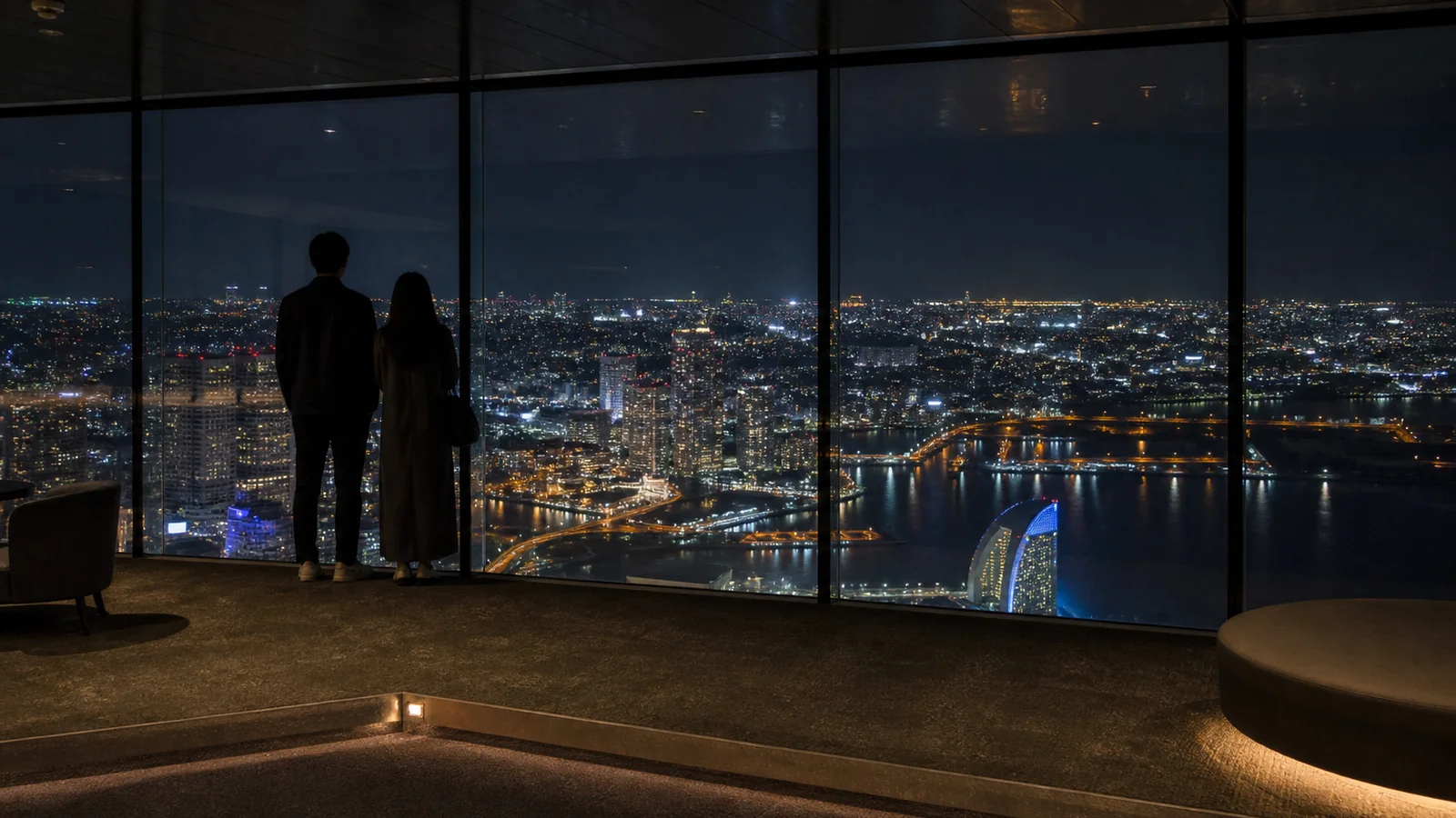 展望フロアの窓越しに横浜の夜景を眺めるカップル
